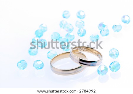 Two wedding rings and a glassy beads with reflections.