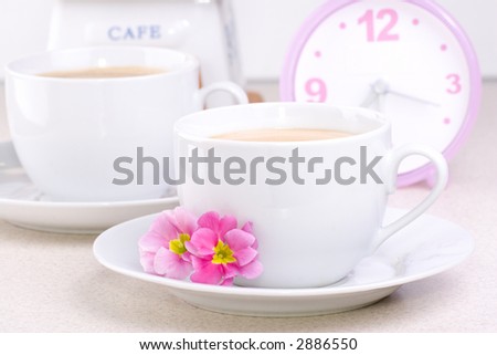 Two cups of coffee (could be a cocoa) and a clock.