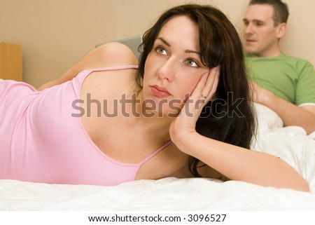 Woman thinking and man using laptop in the background
