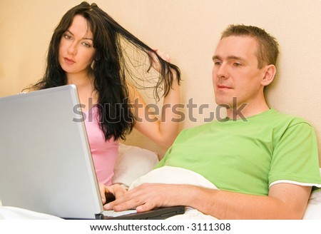 Couple in the bed browsing internet, woman has wet hair.