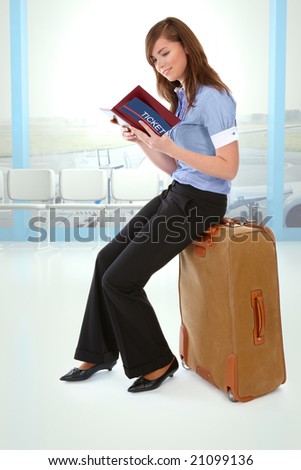 Tourist girl sitting on a suitcase with a ticket and notebook in her hand