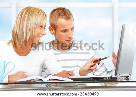 Portrait of a happy couple with laptop in home or office