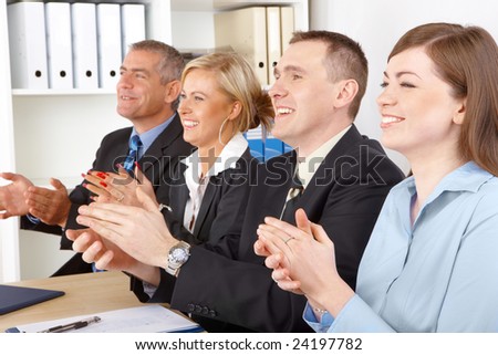 Smiling business group clapping hands at the meeting