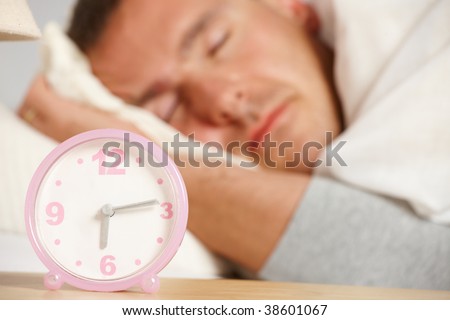 Sleeping man with the clock in the foreground.