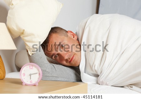 Sleeping man. His hand with pillow, ringing clock showing morning.