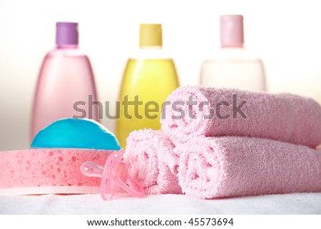 Baby care objects. Olive, shampoo, soap in background towels, sponge, soap and dummy