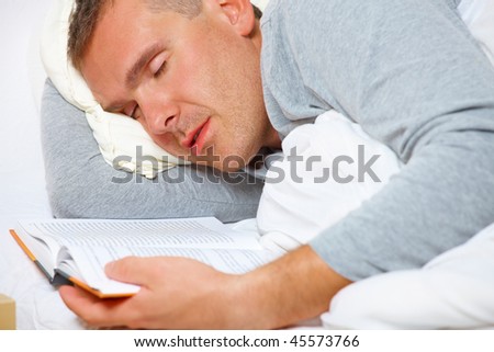 Sleeping man with open book on the bed