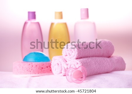 Baby care objects. Olive, shampoo in background towels, sponge, soap and dummy