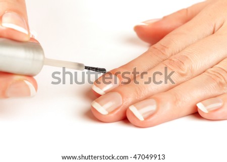 Manicurist applying natural looking nail polish on female fingers in the process of french manicure