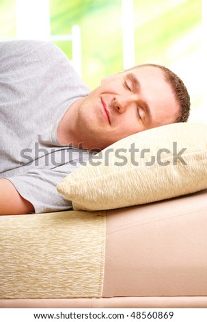 Sleeping man with pillow under head, laying on sofa in home. Indoors color image, vertical orientation.