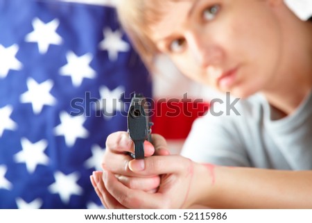 Woman with gun aiming at something, US flag in background
