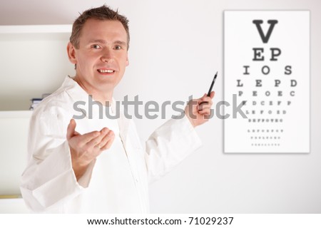Male oculist doctor examining patient with an eye chart behind him.