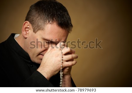 Praying priest with rosary in his hands