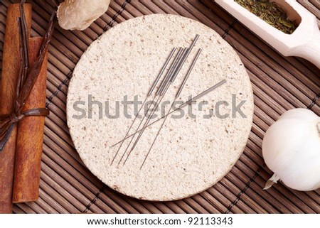 Acupuncture needles laying on the stone mat and herbs like garlic. TCM Traditional Chinese Medicine concept photo