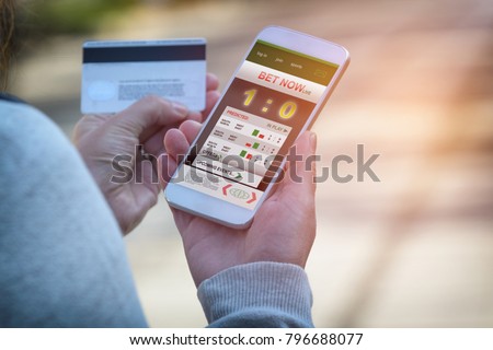 Man betting on sports, holding smart phone with working online betting mobile application