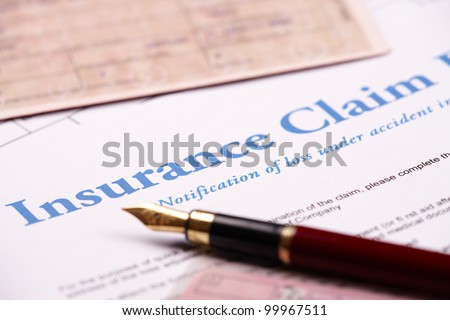 Blank insurance claim form and other papers like ID or vehicle documents and pen lying on desk