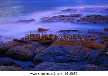 pre-dawn at the beach, water rolling in mist effect, rocks glowing,  stunning shot.