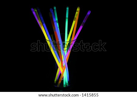 A glass filled with multiple coloured glow sticks