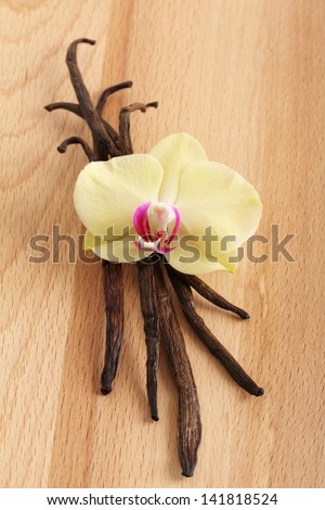 Vanilla pods and flower on a wooden background