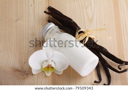 Vanilla pods, flower and bottle on a wooden background
