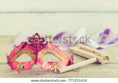 Purim jewish holiday composition with purim mask and purim gragger or a noisemaker on a vintage wood background with copys pace