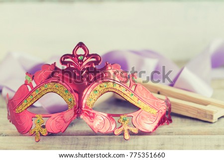 Purim jewish holiday composition with purim mask and purim gragger on a vintage wood background with copys pace