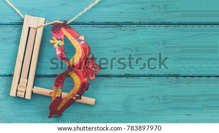 Purim jewish holiday composition with purim mask and purim gragger or a noisemaker hanging on a rope against a vintage wood green background with copy space