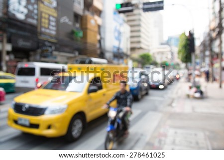 Blurred unfocused city view at day time. Unfocused cars in the way. Unfocused yellow car.