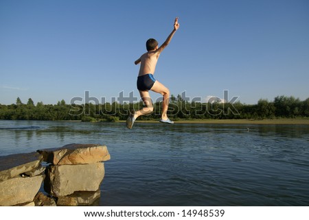 Boy jumps in water from a stone