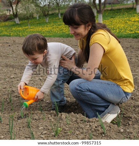 Boy watered plants with his mother