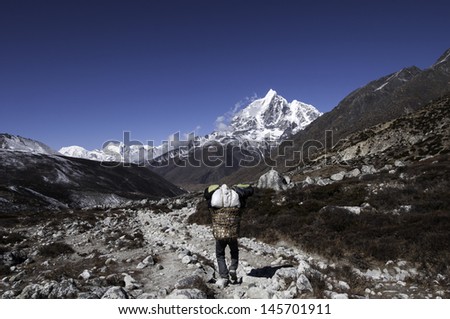 Mountain porter carrying heavy load in Himalayas, Nepal