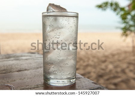 Glass of cold mineral water on the table of the beach background