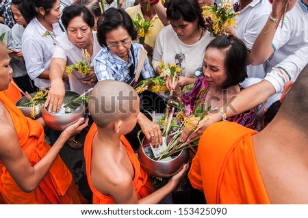 SARABURI, THAILAND-JULY 22: Crowd of unidentified people offer flowers to unidentified monks in Buddhist ceremony at Phrabuddhabat temple on July 22, 2013 in Saraburi, Thailand.