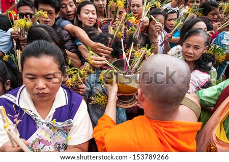 SARABURI, THAILAND-JULY 22: Crowd of unidentified people offer flowers to unidentified monks in Buddhist ceremony at Phrabuddhabat temple on July 22, 2013 in Saraburi, Thailand.