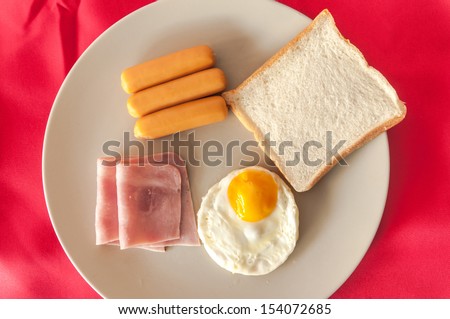 american breakfast with egg,ham,bread and sausage on red cloth