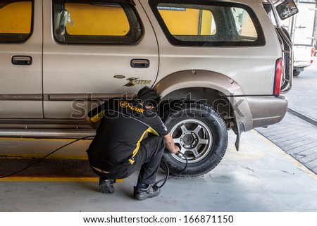 BANGKOK-DEC 06:The car mechanic check the tire at B-Quik garage on December 06,2013 in Bangkok,Thailand.