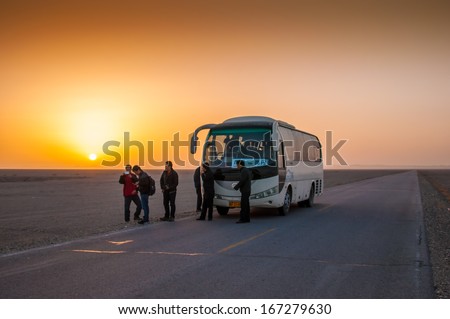 DUNHUANG,CHINA-OCTOBER 17: The tourist bus stop with sunrise on the road to Yadan landforms on October 17, 2013 in Dunhuang, Gansu, China. Yadan Landforms is physiognomy landscape.