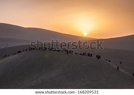 DUNHUANG,CHINA-OCTOBER 16:The visitors waiting for sunset in the Mingsha sand dunes mountain on October 16, 2013 in Dunhuang, China.