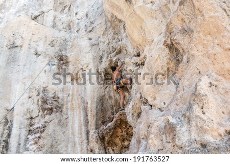 Krabi,Thailand - March 29, 2014: Rock climber climbing on Railay beach in Krabi, Thailand. Railay beach is one of the most popular rock climbing locations in Asia.