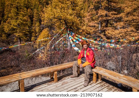 Man at Colorful autumn forest in Yading national level reserve, Daocheng, Sichuan Province, China.