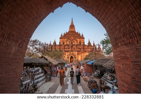 Bagan,Myanmar-March 19,2011 : Htilominlo Temple entrance with tourist passing by street market to enter the temple in Bagan, Myanmar.This large temple was built by King Nantaungmya in 1218.