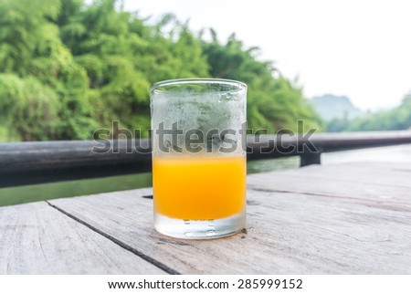 Half of orange juice glass on the table of the natural background