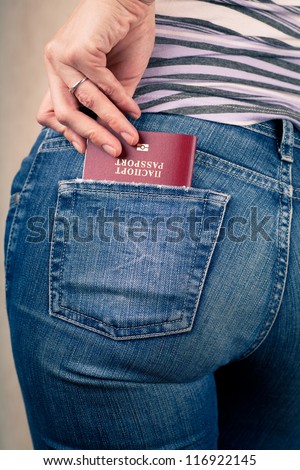 Shot of young woman behind in worn out jeans and passport in a pocket