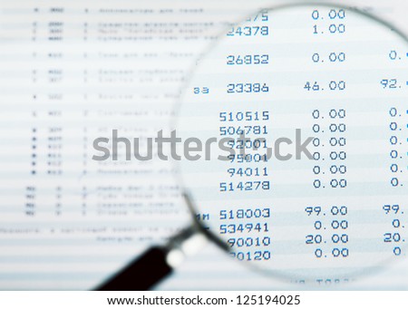 Closeup view of magnifying glass looking at financial report Closeup view of magnifying glass looking at financial report