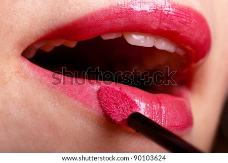 Girl applying lip gloss using lip brush