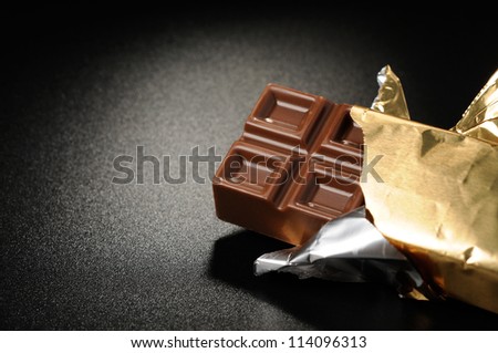 Open bar of chocolate on a black textured background