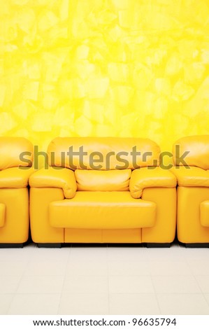 Yellow leather armchairs in waiting room and yellow textured wall