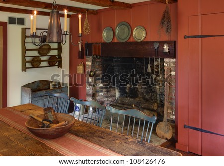 The dining room in a primitive colonial style reproduction home, built with materials reclaimed from structures built in the late 1700\'s.  The room contains many antiques from the late 18th century.