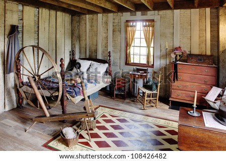 The bed room in a primitive colonial style reproduction home, built with materials reclaimed from structures built in the late 1700\'s.  The room contains many antiques from the late 18th century.