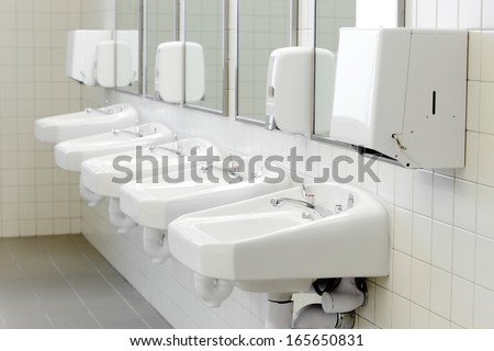 The sinks  in a modern public rest room.